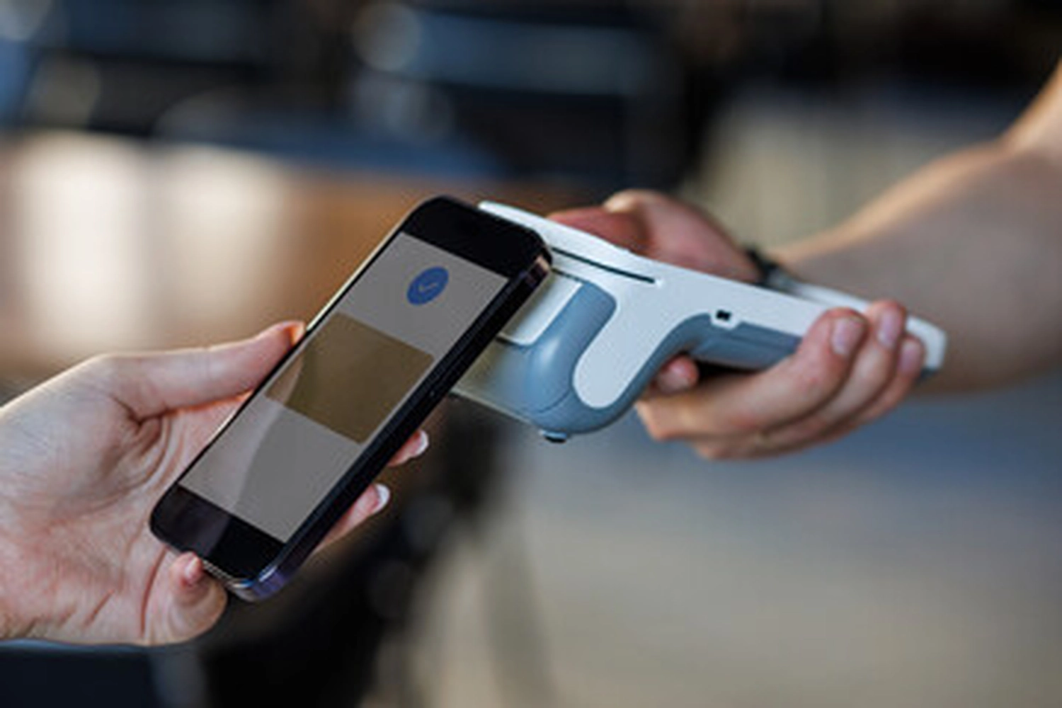Mobile-color-Mobilfunkladen-Ein Kunde führt eine sichere, kontaktlose Zahlung mit einem Smartphone an einem Kassenterminal durch.